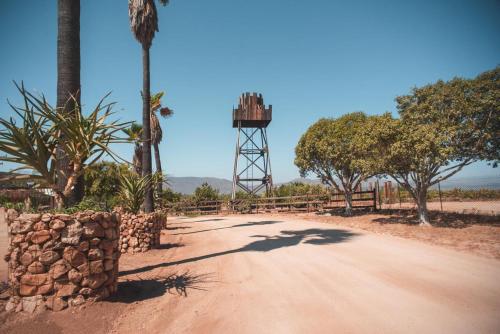 a dirt road with a tower in the distance at Hotel Castillo Ferrer in Valle de Guadalupe