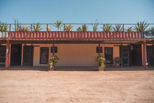 a building with a red roof and a dirt field at Hotel Castillo Ferrer in Valle de Guadalupe