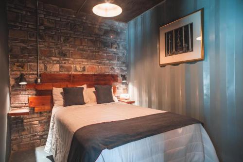 a bedroom with a bed with a brick wall at Hotel Castillo Ferrer in Valle de Guadalupe