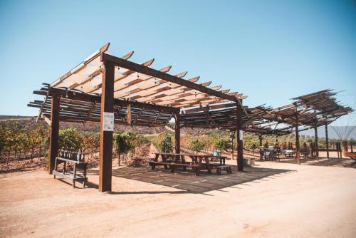 a wooden pavilion with picnic tables and benches at Hotel Castillo Ferrer in Valle de Guadalupe