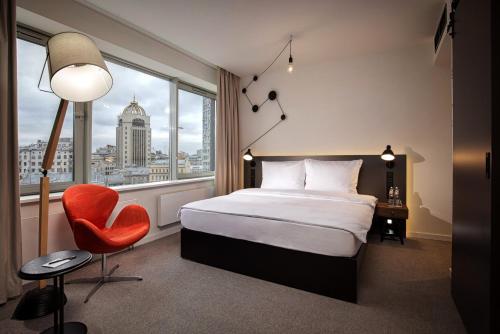 モスクワにあるPentahotel Moscow, Arbatのベッド1台、椅子、窓が備わる客室です。