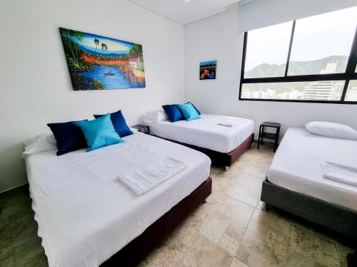 a room with two beds and two windows at Apartasuites VITA 945 RODADERO - By Bedviajes in Santa Marta
