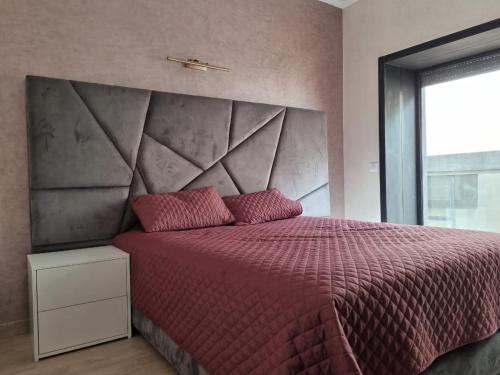 a bedroom with a red bed with a large headboard at Taghazout Bay in Taghazout