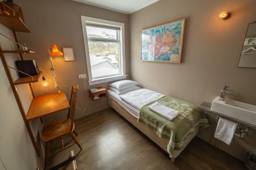 a small room with a bed and a sink and a window at Hotel Siglunes in Siglufjörður