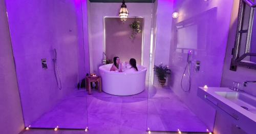 two people in a bath tub in a purple bathroom at Murallas de Jayrán Hotel Boutique in Almería