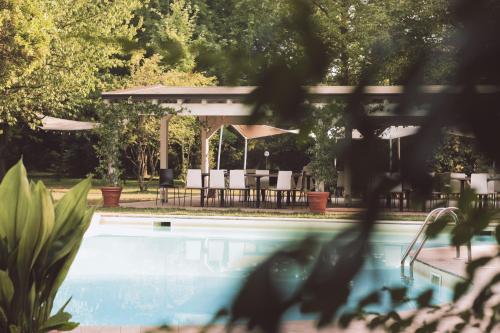 a swimming pool with tables and umbrellas in a yard at Locanda San Martino in San Martino in Rio