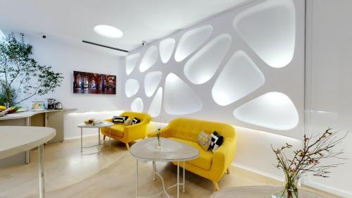 sala de estar con sofá amarillo y mesas en Hotel Boutique Suite Generis, Premiado El hotel más acogedor de España, en Córdoba