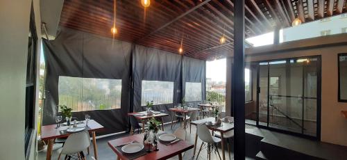 a dining room with tables and chairs and windows at Terra Guest House in Maputo
