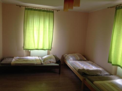 two beds in a room with green curtains at Willa Na Skraju Puszczy in Zaścianki