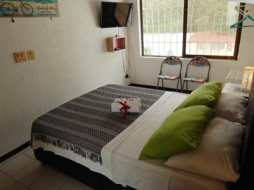 a bedroom with a bed with green pillows and two chairs at 5E Hotel Boutique in Girardot