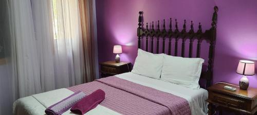 a purple bedroom with a large bed with purple walls at Casa da Oliveira in Milhão