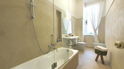 a bathroom with a tub and a toilet and a sink at Heart Milan Apartments Fashion District in Milan