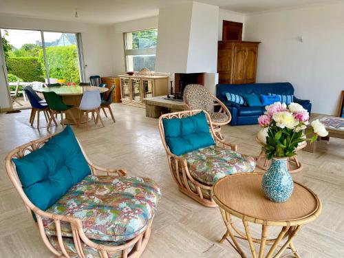 una sala de estar con sillas y una mesa con un jarrón de flores en Villa Simone vue mer 2min à pied de la plage, en Saint-Lunaire