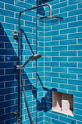 a blue brick wall with a shower in a bathroom at Finolhu, A Seaside Collection Resort, a Member of Design Hotels in Baa Atoll