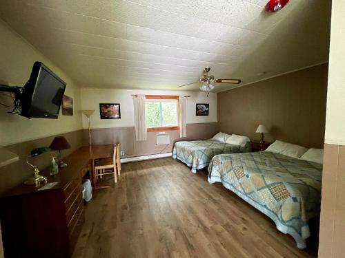 a bedroom with two beds and a desk and a tv at The Riverside Inn in Stowe