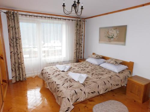 Bett in einem Zimmer mit einem großen Fenster in der Unterkunft Glanz Cottage in Jaremtsche