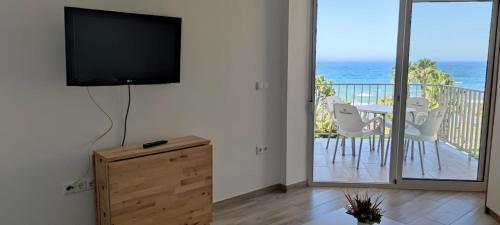 a living room with a tv and a balcony with the ocean at Estudio SHEILA in Torrox Costa
