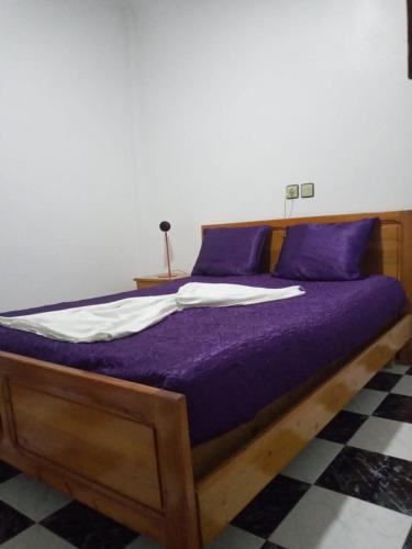 a bed in a room with purple sheets and pillows at L'orientale in Saïdia
