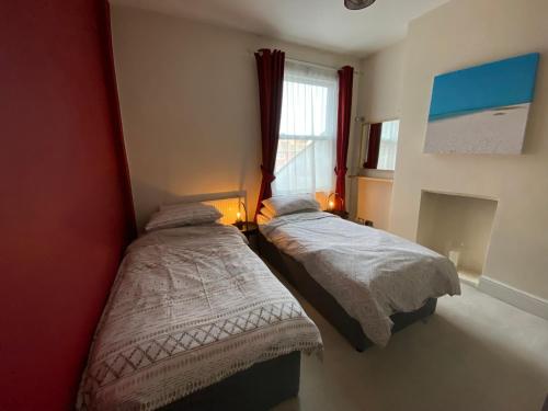 2 Betten in einem kleinen Zimmer mit Fenster in der Unterkunft 3 bed Apartment in Colliers Wood in London