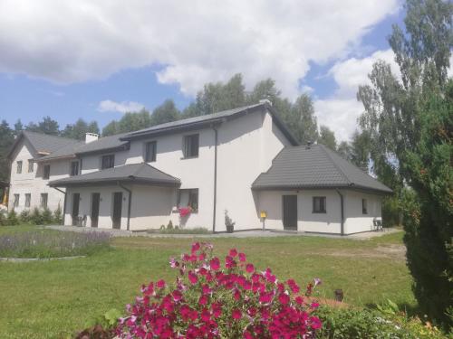 a white house with a yard with flowers at Leśny Apartament II in Szczytno