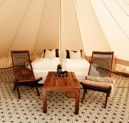 une tente avec un lit, deux chaises et une table dans l'établissement GLAMPNORD, à Bodø