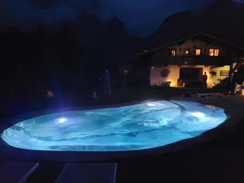 a hot tub with lights in a yard at night at Aqua Apartments Spa Housemuhlbach in Sappada