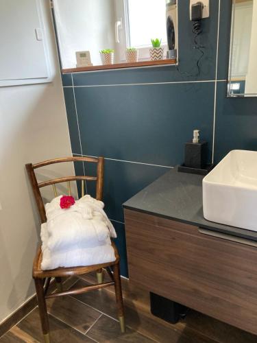 a bathroom with a chair with a sink and a mirror at Petite maison de campagne in Plouëc-du-Trieux