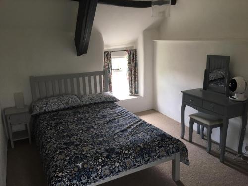 Un dormitorio con una cama y un escritorio y una ventana. en Picture perfect cottage in rural Tintagel, en Tintagel