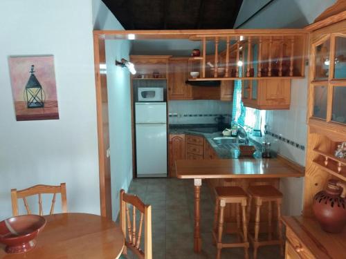 una cocina con armarios de madera, mesa y sillas en Room in Guest room - Casa El Cardon A2 Buenavista del Norte, en Buenavista del Norte