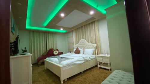 - une chambre avec un lit blanc et une lumière verte dans l'établissement Golden Rose Hotel, à Naplouse