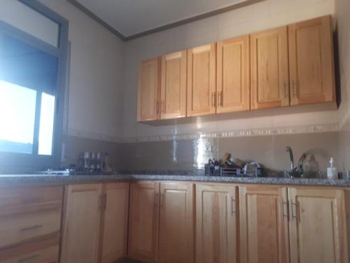 una cocina con armarios de madera y una ventana en Appartements proches de la mer Boukidan Al Hoceima, en Alhucemas