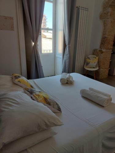 a bed with two rolled towels on it with a window at Sapore di Sale - Sicily Rooms in Siracusa
