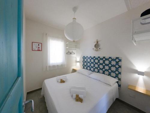 a bedroom with a white bed with a blue headboard at Albarìa Favignana Apartments in Favignana