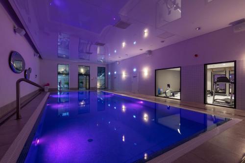 a large swimming pool in a building with purple lighting at Antares Hotel in Gdynia