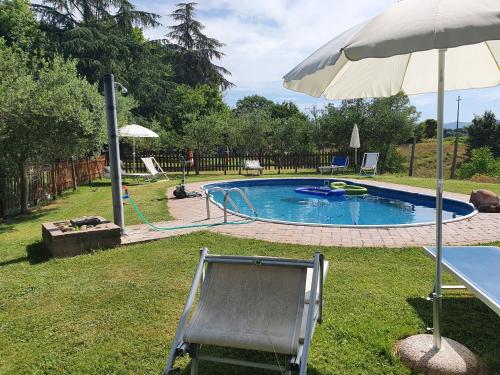 a chair and an umbrella next to a swimming pool at Casa Giogo in Arezzo