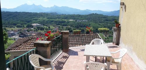 a balcony with a table and chairs and mountains at Casa sotto il Castello in Monti di Licciana Nardi
