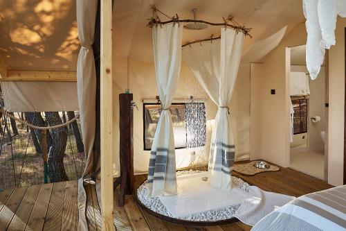 een slaapkamer met een bed met gordijnen en een raam bij Abeille Maison Glamping Resort Zlatni Rat -Adults Only in Bol