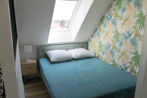 a bed with two pillows in a room with a window at Cabourg - Studio cosy à 1 min de la plage in Cabourg