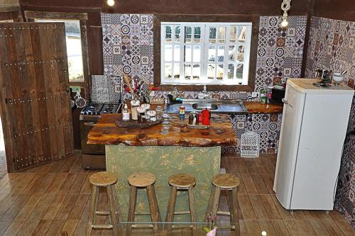 eine Küche mit einer Theke mit Hockern und einem Kühlschrank in der Unterkunft Middle House in Campos do Jordão