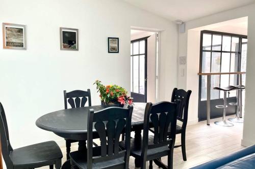 une salle à manger avec une table et des chaises noires dans l'établissement en plein coeur de Talmont, maison connectée à l'esprit rétais, à Talmont-sur-Gironde