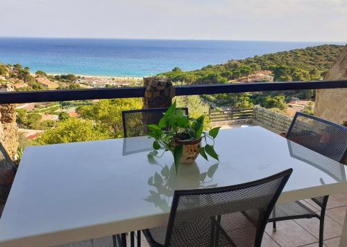 una mesa con una maceta en un balcón con vistas al océano en Villetta con piscina panoramica Belvedere Mari Pintau, en Geremèas