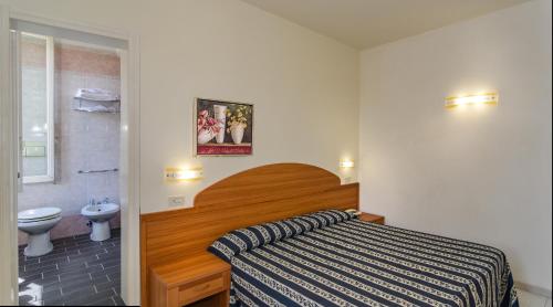 1 dormitorio con 1 cama y baño con aseo en Hotel Apuana, en Marina di Pietrasanta