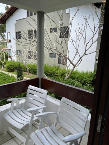 two white chairs sitting on a balcony with a window at Flat no hotel fazenda portal de Gravatá in Gravatá