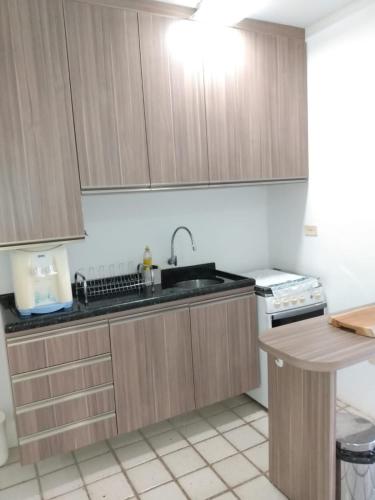 a kitchen with wooden cabinets and a sink at Flat no hotel fazenda portal de Gravatá in Gravatá