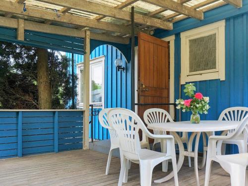 6 person holiday home in MARIESTAD في مارياستاد: منزل أزرق على طاولة وكراسي على السطح