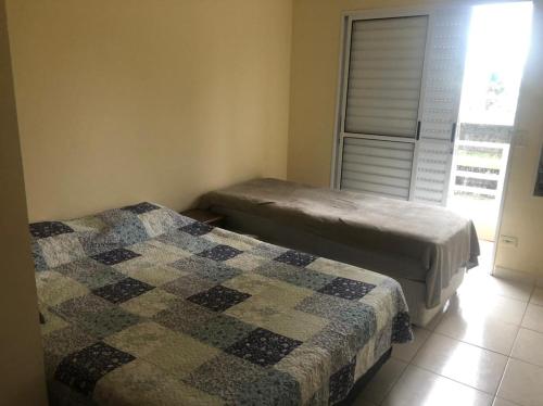 Dos camas sentadas en una habitación con ventana. en Linda Casa pé na areia em Mongagua, en Mongaguá