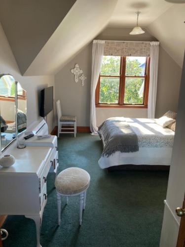 a bedroom with a bed and a desk and a window at Taiparoro House in Tauranga