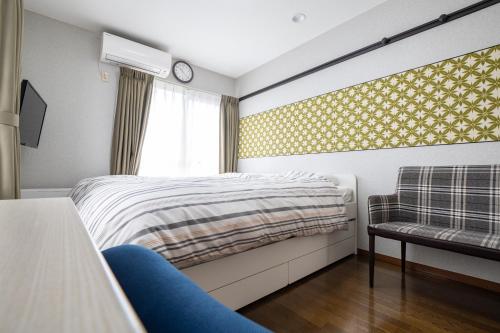a bedroom with a bed and a chair and a window at ローズパーク弐番館 in Funabashi