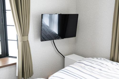 a flat screen tv on the wall of a bedroom at ローズパーク弐番館 in Funabashi