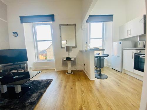 a kitchen with white cabinets and a hard wood floor at The Sleeping Lion - Dunoon Holiday Home in Dunoon